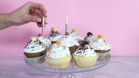 putting candles on cup cakes with cream for birthday party