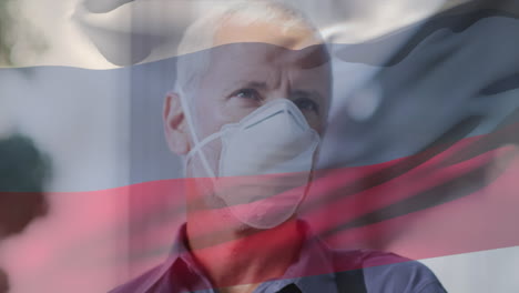 animation of flag of russia waving over man wearing face mask during covid 19 pandemic