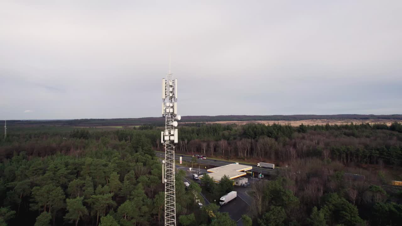 Paesaggio che contrappone la torre radio bianca, l'antenna tecnica per la comunicazione e la trasmissione dati nel parco naturale di Veluwe, illuminata lateralmente e in contrasto con il verde e il cielo blu