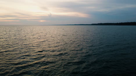 Slow-motion-aerial-dolly-above-coastal-water-ripples-with-gentle-soft-yellow-light-on-wave-peaks