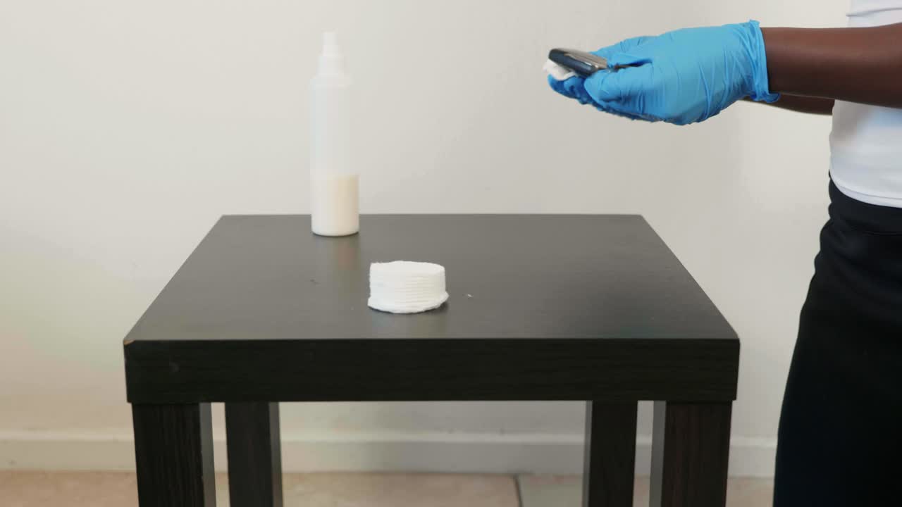 African lady disinfects keys wearing gloves during covid19