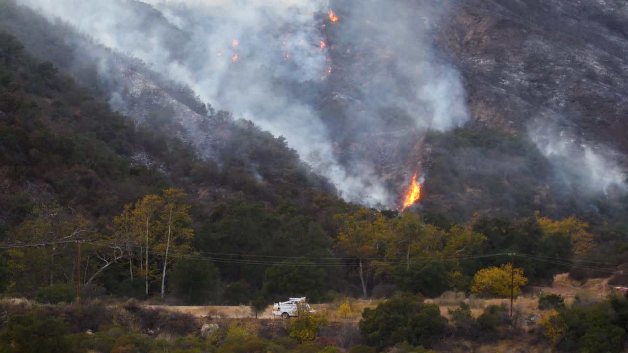 el incendio de thomas arde en las colinas y roza sobre ojai california con un camión edison del sur de california pasando en primer plano