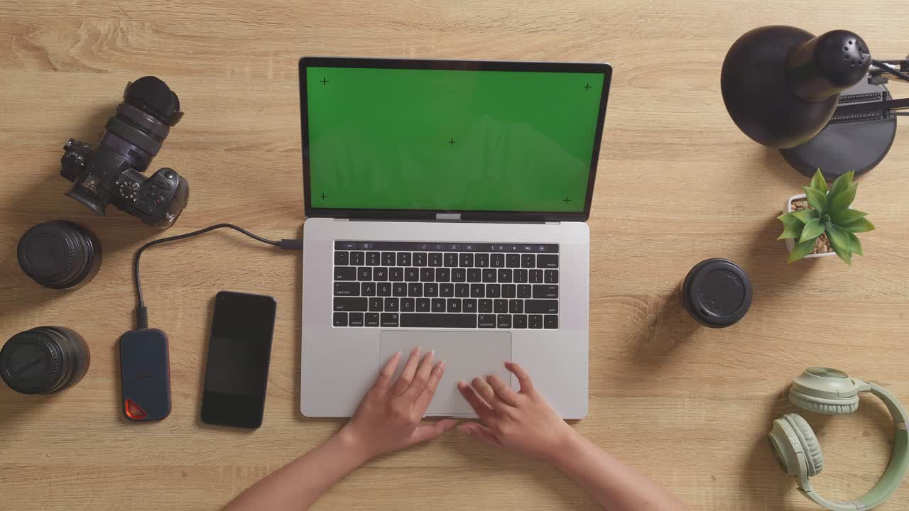 vista de arriba hacia abajo de una estación de trabajo con portátil, cámara y otros accesorios