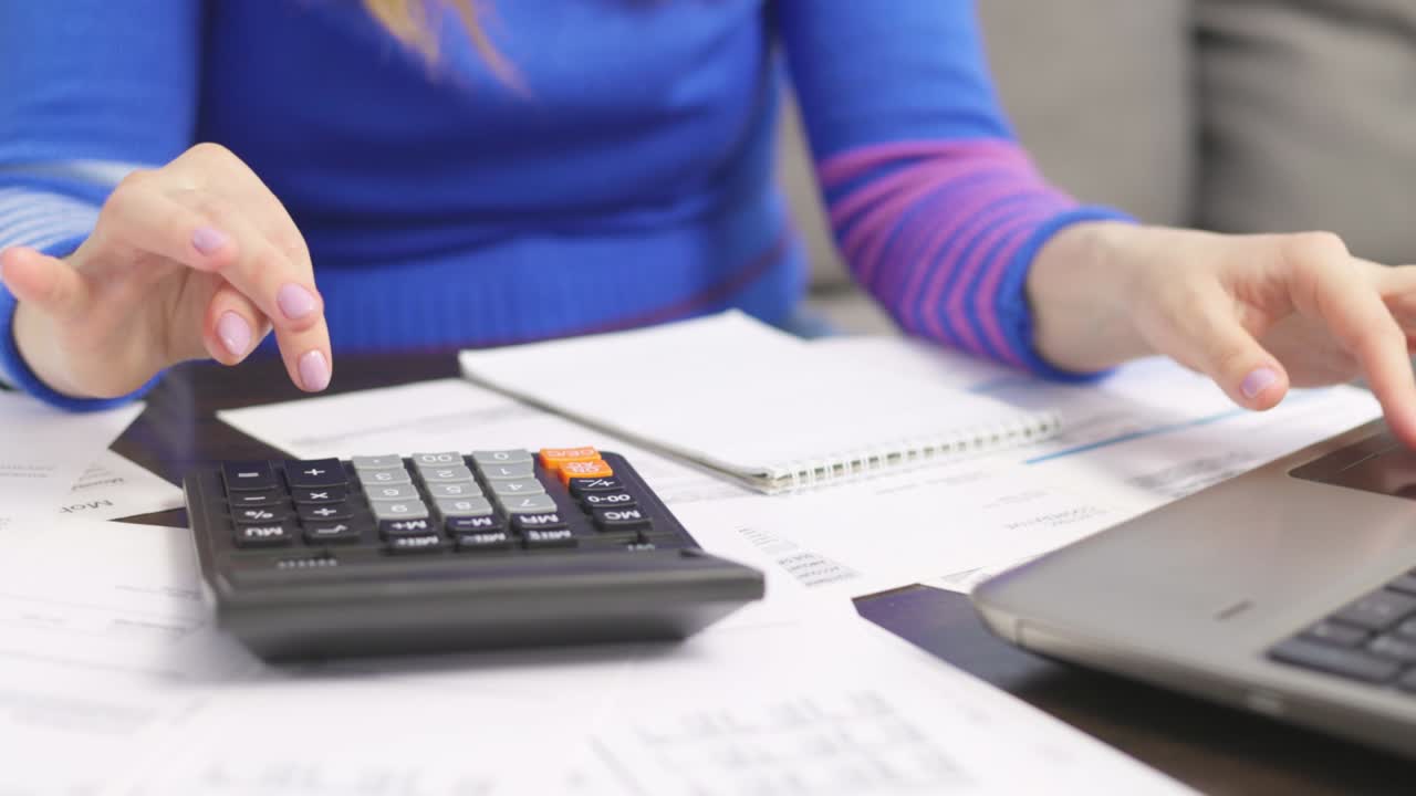 mujer usando calculadora para calcular facturas domésticas en el hogar, haciendo papeleo para pagar impuestos