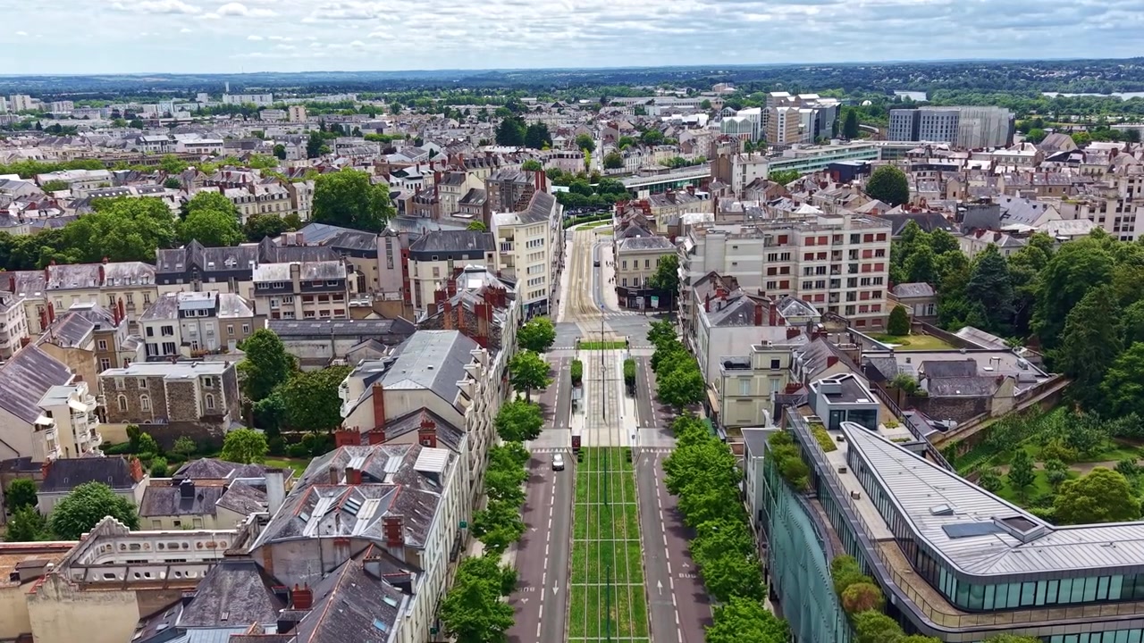 Dron volando sobre el Boulevard du Maréchal Foch, revelando el corredor del tranvía, los edificios circundantes y el centro de Angers, Francia