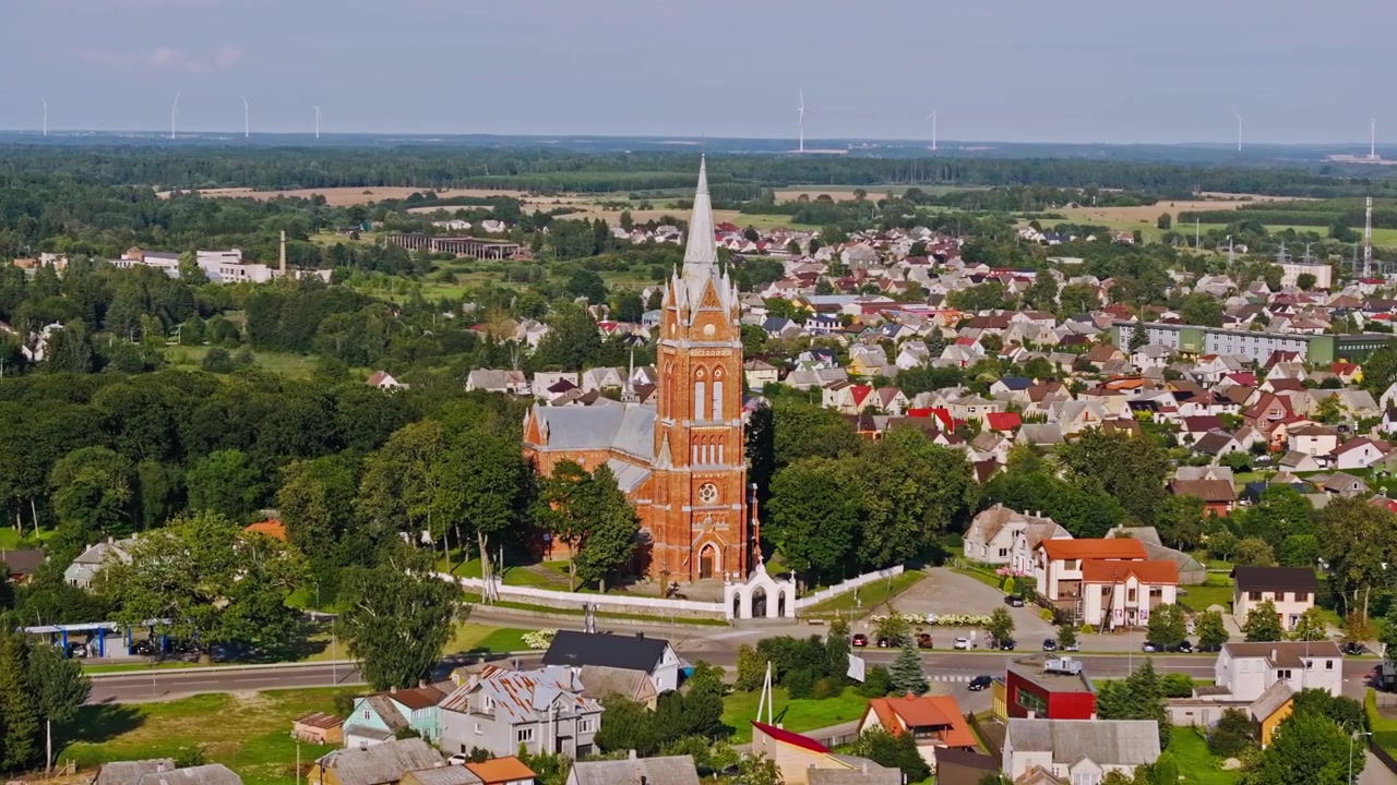 Órbita aérea sobre la Iglesia de Kelmė y el paisaje de energía renovable en verano