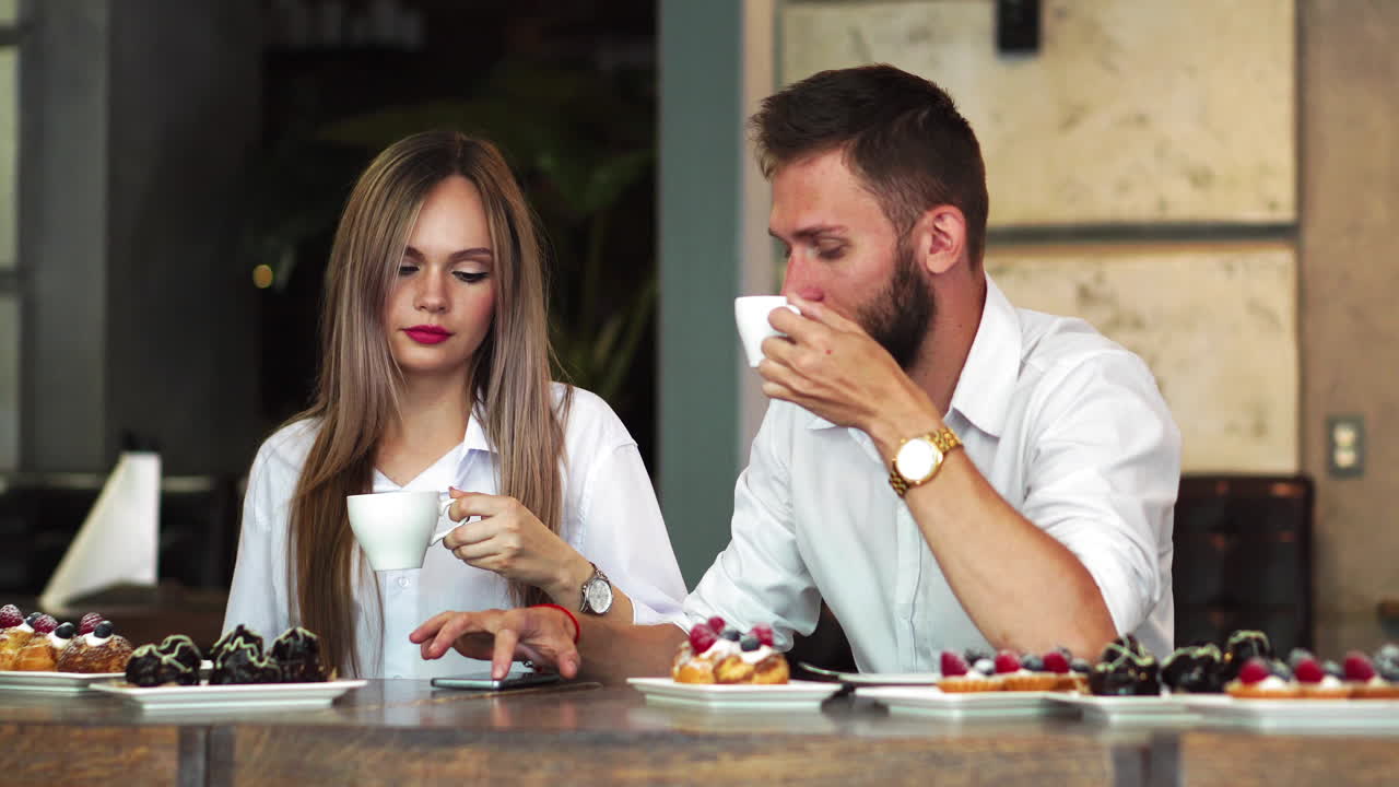 Man and woman at the bar having a coffee and using a mobile phone