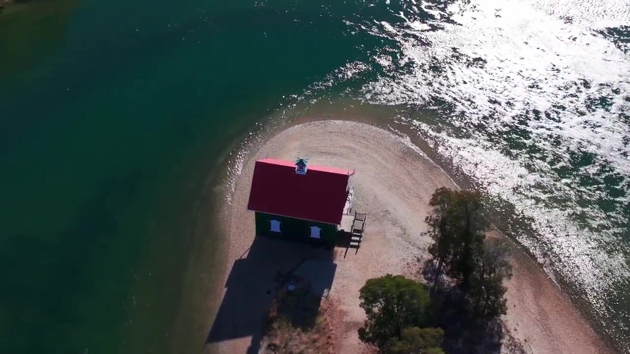 Una vista aerea di Gamecock Cottage, un edificio storico costruito nel 1876 nella contea di Suffolk, NY, in una giornata di sole. La telecamera si è inclinata verso il basso, ha zoomato e ha effettuato un carrello a destra orbitando attorno al cottage e alle zone umide circostanti.