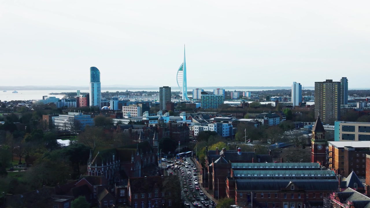 Riprese aeree con drone delle strade della città di Portsmouth con una torre dell'orologio, traffico e un treno di passaggio sotto lo skyline della Spinnaker Tower