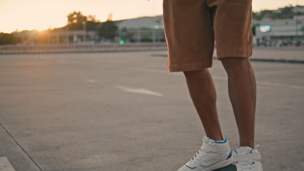 patinador chico balanceando la tabla al atardecer en primer plano. zapatillas de deporte hipster patinaje de pie
