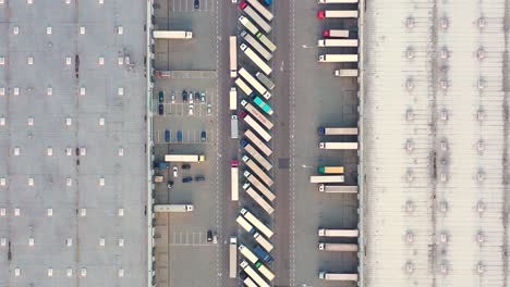 aerial view of a semi trucks with cargo trailers standing on warehouses ramps for loading unloading goods on the big logistics park with loading hub