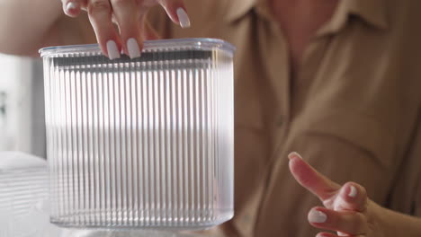 Woman-puts-lid-on-plastic-container-and-examines-utensil