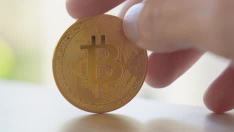 close-up of a hand holding a gold bitcoin