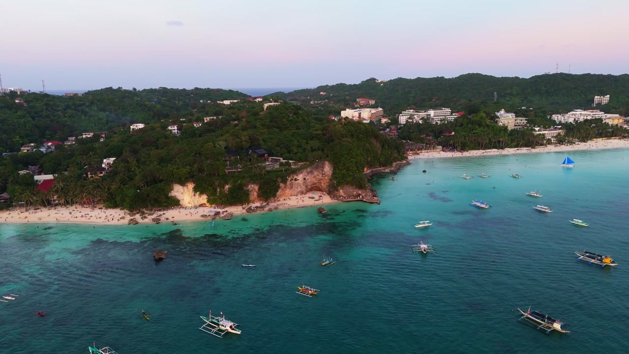 Aerial dolly in over Boracay sea, sailing boats and cliff resorts, Philippines, white sand beach tropical travel coastline
