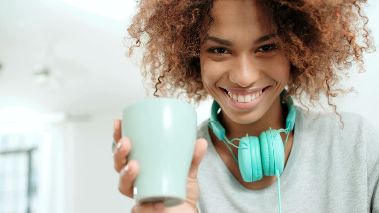 una joven afroamericana feliz con auriculares posando para una cámara.