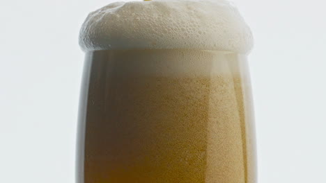 craft beverage pouring transparent glass closeup. stream making foam drink