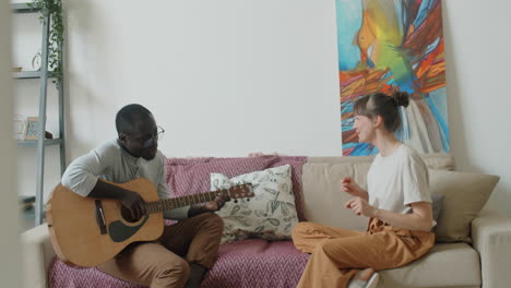 African-American-Man-Playing-Guitar-and-Singing-and-Wife-Dancing-on-Sofa