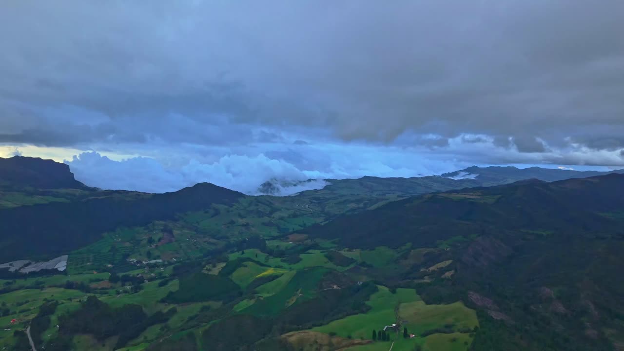 Drone advances toward dense clouds above Zipaquira mountains and green valleys