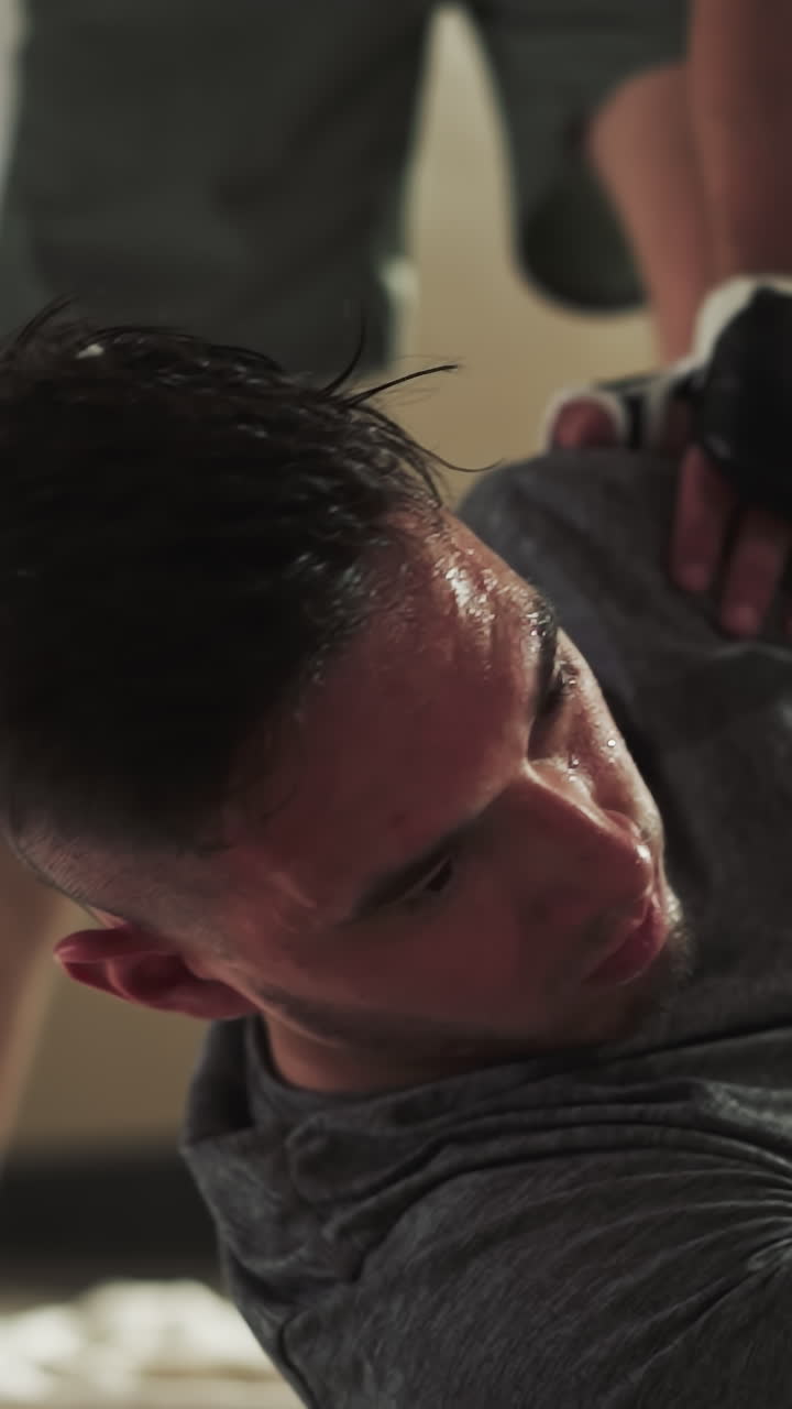 패배한 남자는 스포츠 클럽의 바닥에 무거운 타격을 받고 있습니다. 고통받는 스포츠맨은 무술 체육관에서 불공평한 전투에서 느린 동작으로 패배합니다. 공격적인 스파링.