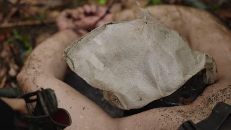 waterboarding interrogation with hooded, restrained man on forest ground