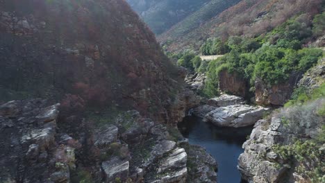 Drone-shot-flying-backwards-and-up-out-of-mountain-gorge-with-freshwater-pools-in-Karoo