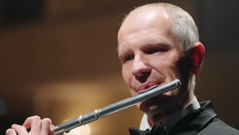 portrait of aged flutist in opera house closeup view of male face with flute classic music concert