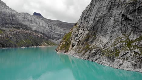 sobrevuelo aéreo sobre las aguas turquesas del lago limernsee y la represa hidroeléctrica en linthal glarus, suiza con vistas al paisaje lleno de acantilados