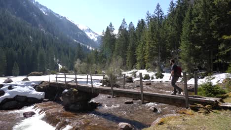 still shot of a young man walking over a bridge on a valley in the swiss alps in slow motion