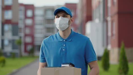 An-young-mailman-courier-with-a-protective-mask-and-gloves-is-delivering-a-parcel-directly-to-a-customer-home-with-safety.-Concept-of-courier-home-delivery-e-commerce-shipping-virus-covid