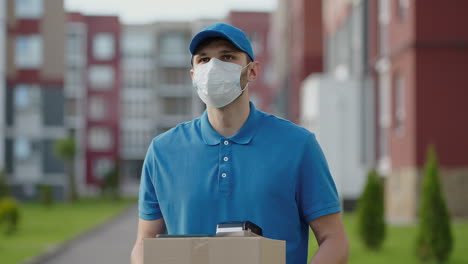 an young mailman courier with a protective mask and gloves is delivering a parcel directly to a customer home with safety. concept of courier home delivery e-commerce shipping virus covid