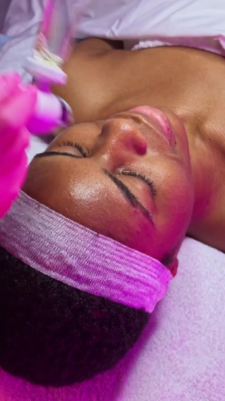 Femme recevant un soin de la peau dans un spa, avec une seringue et une lumière violette, dans une clinique esthétique en soirée.