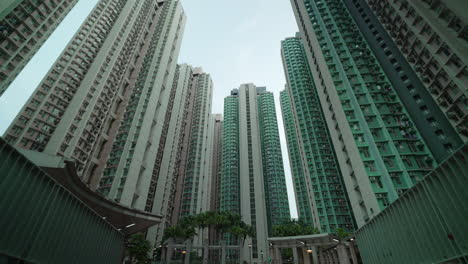 bottom up dolly showing gigantic skyscraper residential blocks in hong kong city against clouds