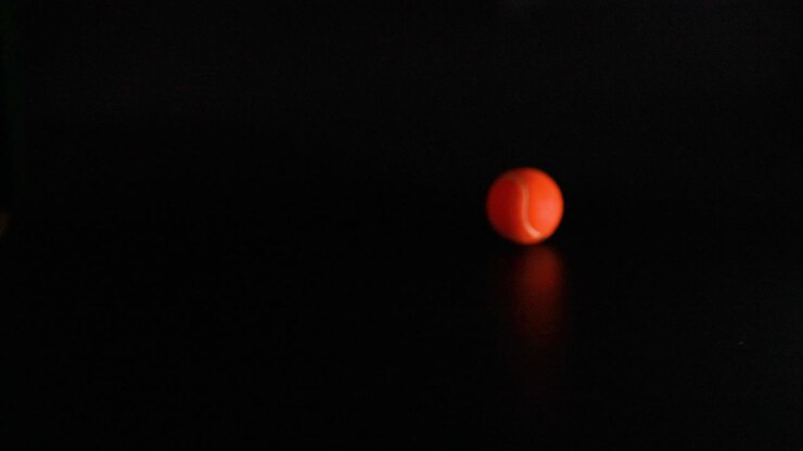 A tennis ball bounces on a dark surface