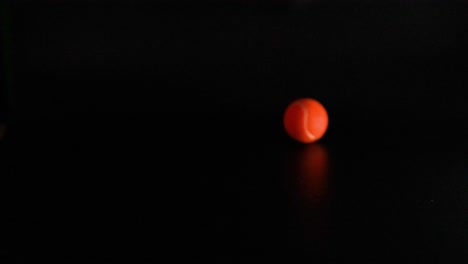 una pelota de tenis rebota en una superficie oscura