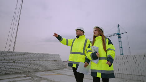 young female architect and male civil engineer are walking in construction site