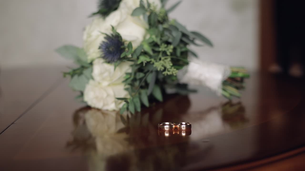 The groom's hand takes a wedding bouquet that lays on the table