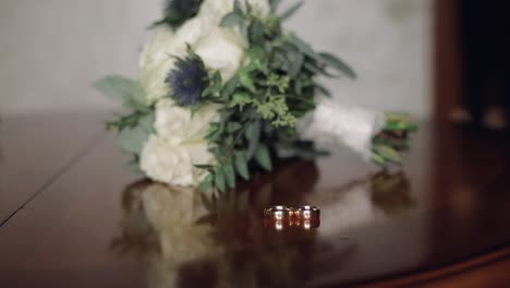 The-groom's-hand-takes-a-wedding-bouquet-that-lays-on-the-table