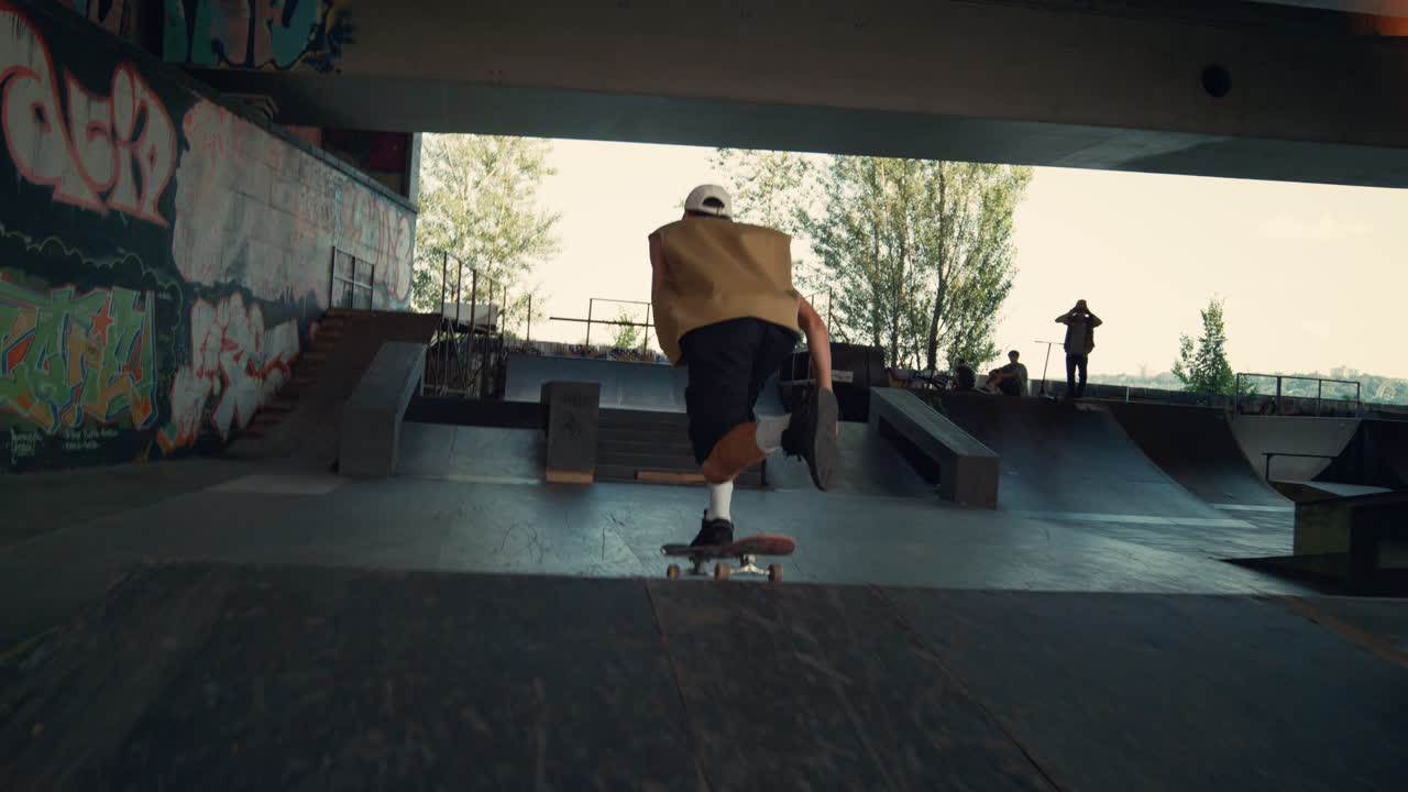 un joven patinador montando en patineta en el parque de patinaje de la ciudad. un niño saltando en patineta.