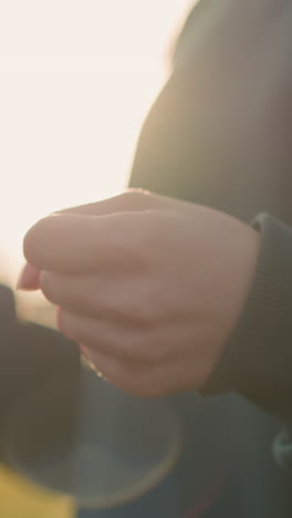 초록색 옷을 입은 여자의 클로즈업은 초록색과 건물을 보여주는 흐릿한 배경으로 손목을 회전시켜 야외 환경에서 손의 움직임을 강조하고 초점을 맞추고 있습니다.