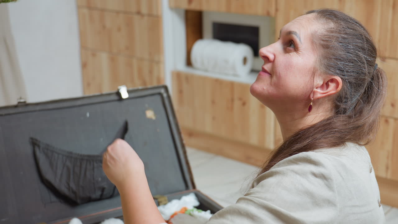 Woman sitting on floor stretching hand handing christmas ornament to boy partial view, festive preparation atmosphere, cozy holiday mood, joyful indoor celebration near decorated tree