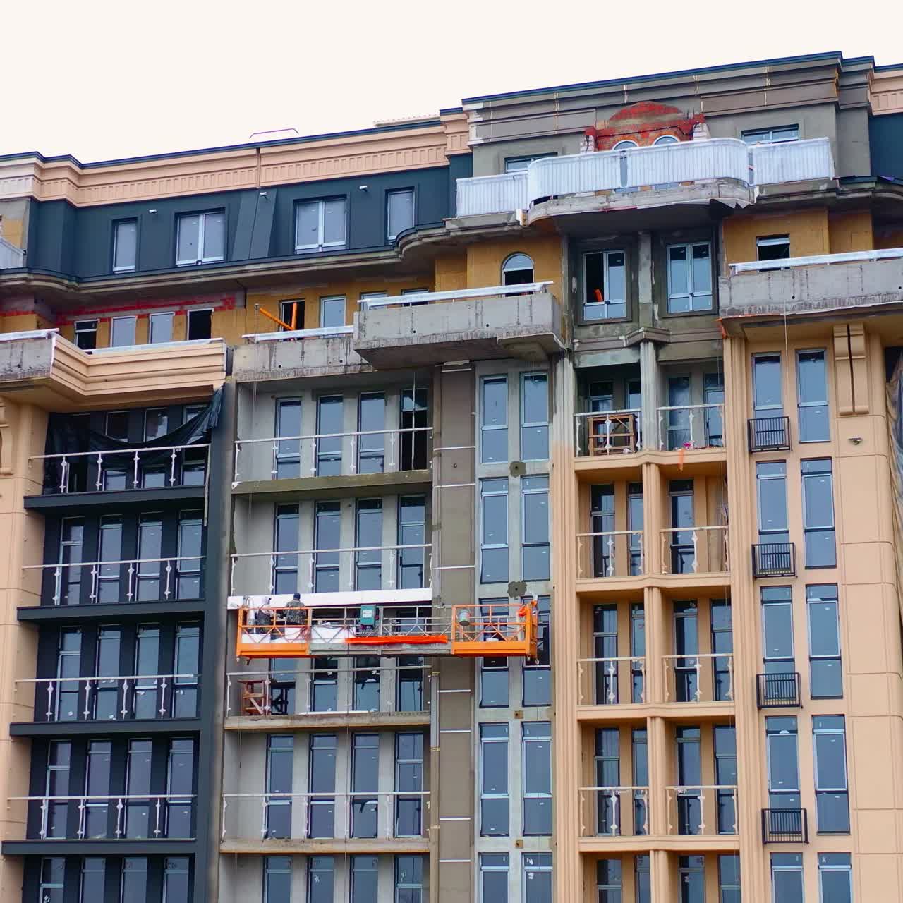 Building of a modern block of flats. Construction of a tower building in the city. Front view of a high-rise architecture.