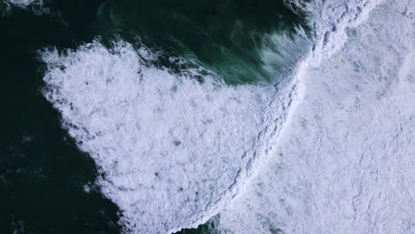 massive atlantic swells crash onto coastline, whitewash in shallows