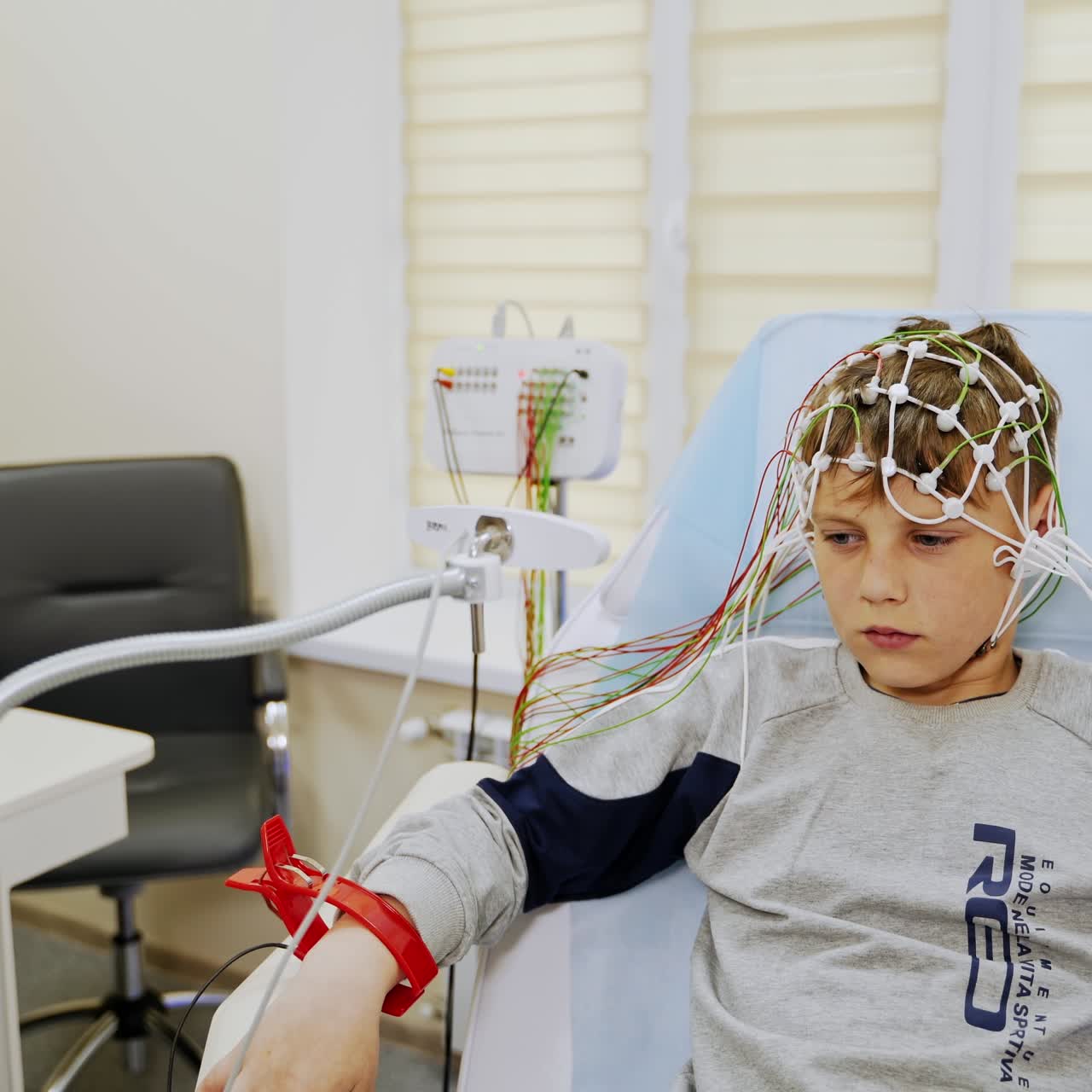 Adolescente sério usando sensores na cabeça e clipes especiais nos pulsos. Médico prepara equipamento para teste de EEG