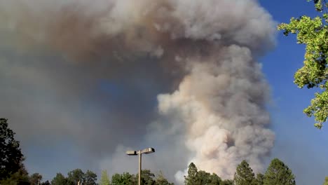 ominous plume of smoke rising in sky from wildfire in california