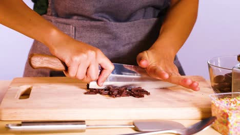 person chopping chocolate discs with a knife