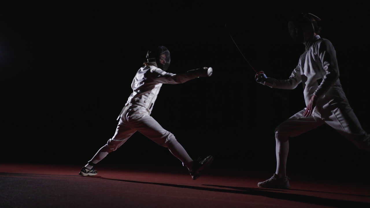 두 명의 펜싱 선수가 펜싱 경기에서 경쟁합니다.