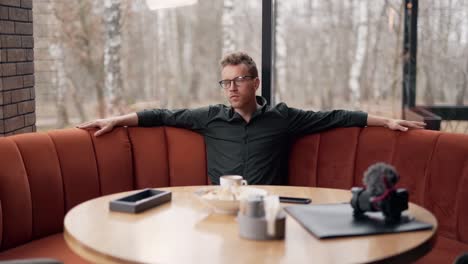 Cute-young-man-meditates-sitting-in-a-restaurant-by-the-window