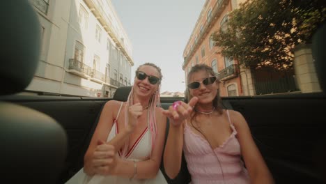 two women celebrating in a convertible car