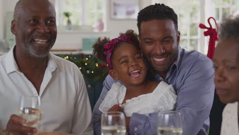 multi-generation family celebrating christmas at home eating meal together