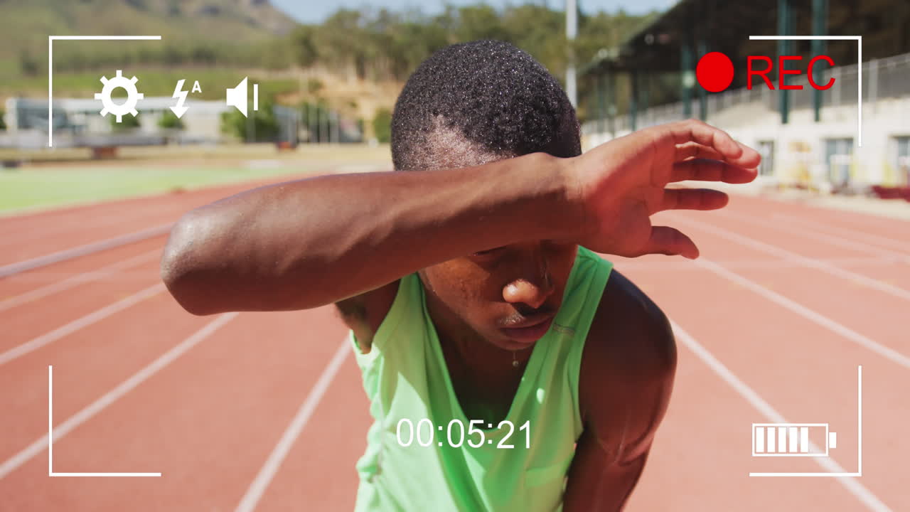 Animation of digital interface with recording screen and african american athlete wiping forehead